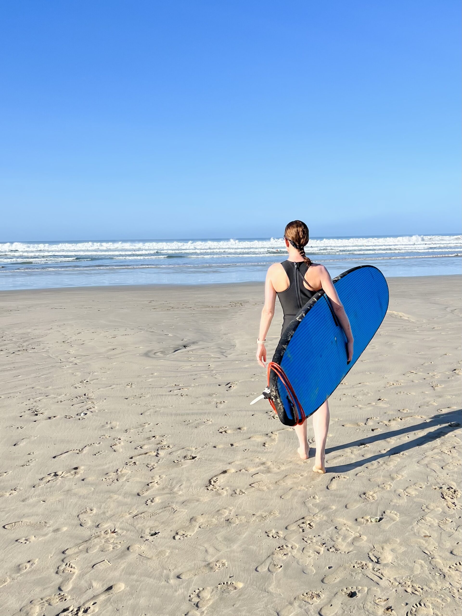 Woman holding surf board on NUSHU Retreat